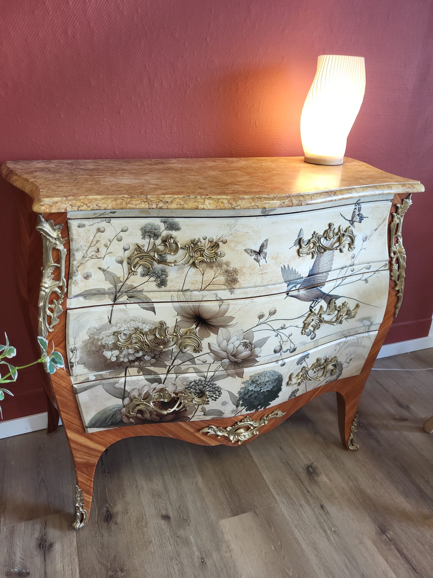 Commode ancienne florale restaurée par celadeco à Toulouse, plateau marbre et lampe cosy sur mur rouge