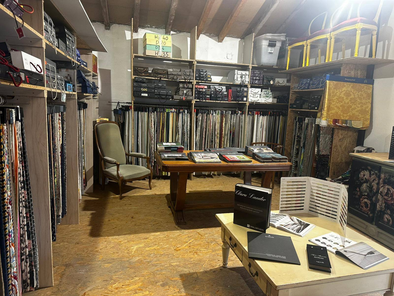 Atelier showroom de tissus d’ameublement Celadeco à Toulouse, table d’échantillons et rouleaux colorés